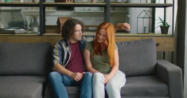 Мужчина и женщина в романтическом настроении расслабляются на диване дома — стоковое видео