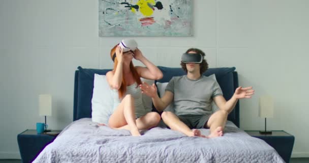 Ungt par underhåller i sängen, tittar på 360 video i VR-headset — Stockvideo