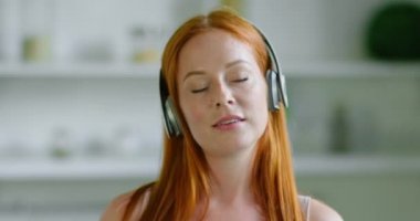 Güzel kızıl saçlı kadın kablosuz kulaklık müzik dinliyor, yakın