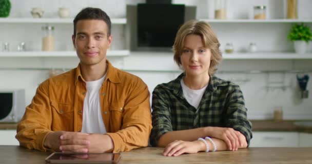 Retrato de jovem casal misto sentado à mesa na cozinha — Vídeo de Stock