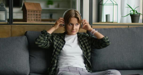 Mujer joven está poniendo auriculares inalámbricos, utilizando la computadora de la tableta — Vídeos de Stock