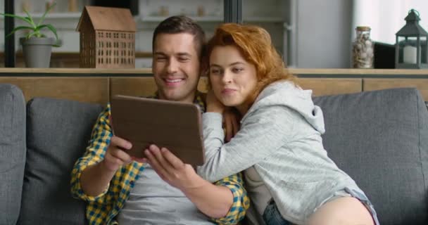 Mladí manželé tráví čas spolu, mají videokonverzaci v tabletovém počítači — Stock video