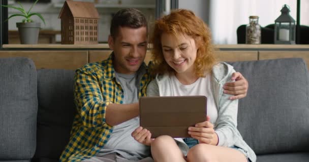 Genç çift, tablet bilgisayar kullanarak, kanepede oturan, online mağaza öğe seçin — Stok video