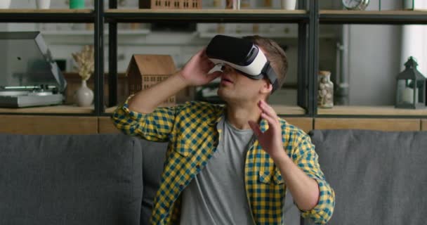 Мужчина наслаждается 360 видео, нося дома гарнитуру виртуальной реальности — стоковое видео