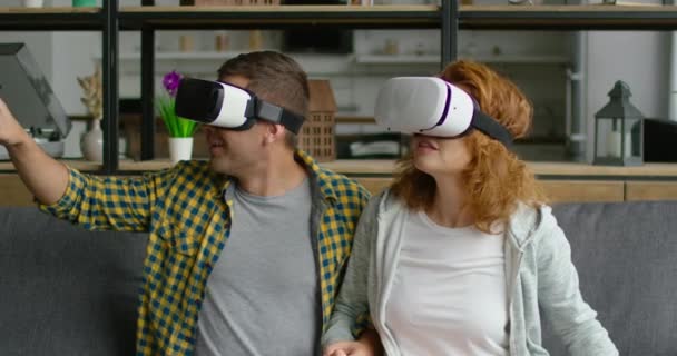 若いカップルは、VRヘッドセットを着用し、クローズアップ360ビデオ画像に感銘を受けています — ストック動画