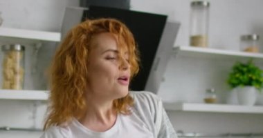 Kızıl saçlı mutlu genç kadın mutfakta dans ediyor, yakın çekim