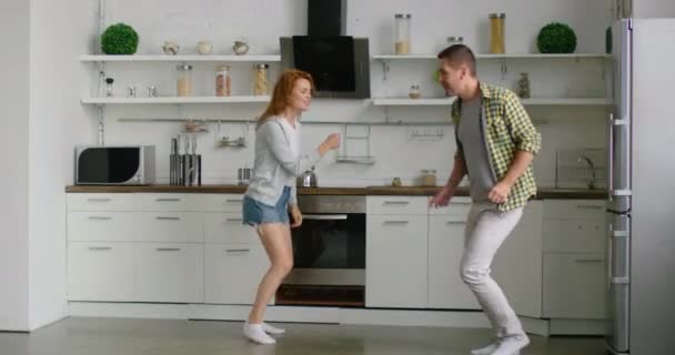 Pareja joven es entretenido en cocina, bailando y divirtiéndose juntos — Vídeos de Stock