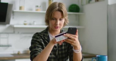 Genç kadın, akıllı telefon ve kredi kartı kullanarak, online alışveriş yapıyor