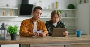 Karışık ırk çift online alışveriş doldurmak, mutfakta masada oturan