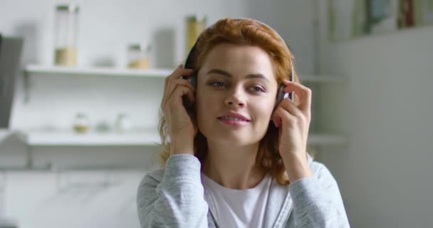 Jonge vrouw zet draadloze headset aan, luister muziek, close-up — Stockvideo
