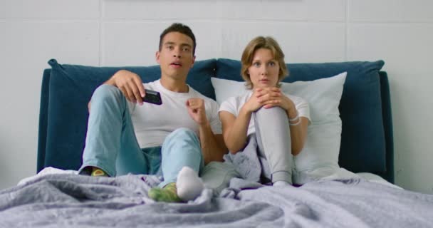 Unga blandade par tittar på sport match i sovrummet — Stockvideo