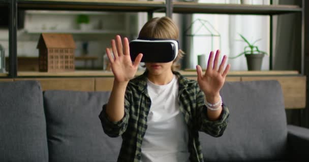 Mujer joven está mirando en sus manos a través de auriculares de realidad virtual — Vídeos de Stock