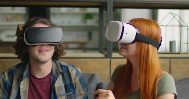 Pareja joven usa auriculares VR en casa, disfrutando de imágenes VR — Vídeo de stock