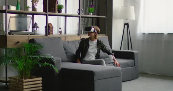 Jovem usa fone de ouvido VR em casa, impressionado com 360 vídeo — Vídeo de Stock