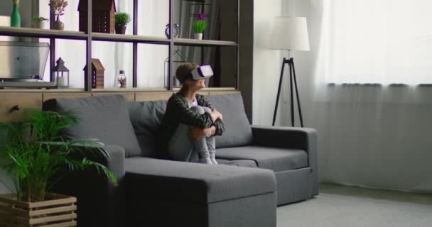 Wanita muda menggunakan headset realitas maya, menghibur sendirian di rumah — Stok Video
