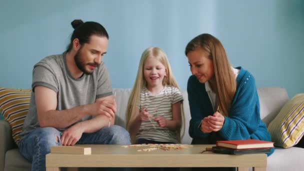 Kleines Mädchen spielt Pick-Up-Sticks mit Eltern — Stockvideo