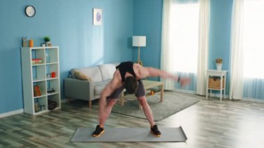 Genç adam yel değirmeni egzersizi yapıyor.