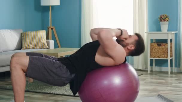 Młody człowiek robi górne chrupki na piłeczce fitness — Wideo stockowe