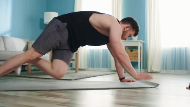 Hombre fuerte está entrenando en casa usando gadget — Vídeos de Stock