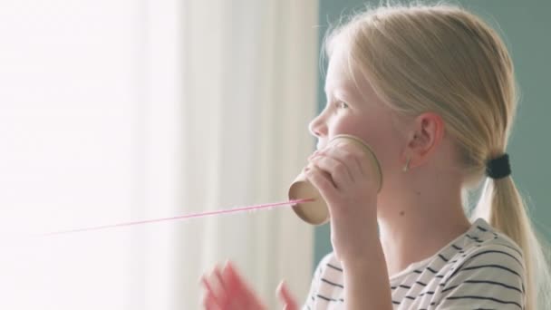 Маленька дівчинка використовує паперовий стаканчик телефон — стокове відео
