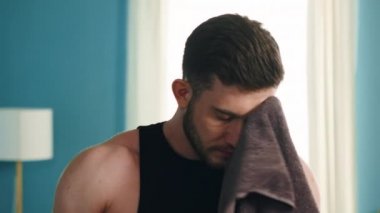 Genç atletik adam yüzünü siliyor.