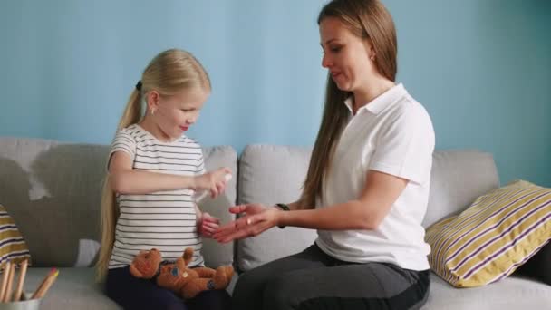 Pequeña niña limpia las manos a su mamá con aerosol antiséptico — Vídeo de stock