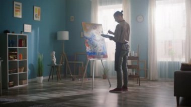 Genç adam tuvalde resim yapıyor.