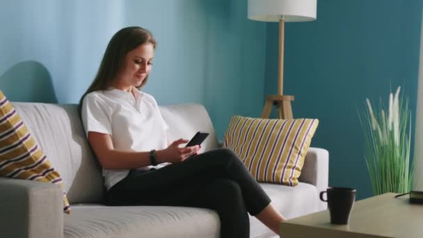 Vrouw is scrollen mobiele telefoon thuis — Stockvideo