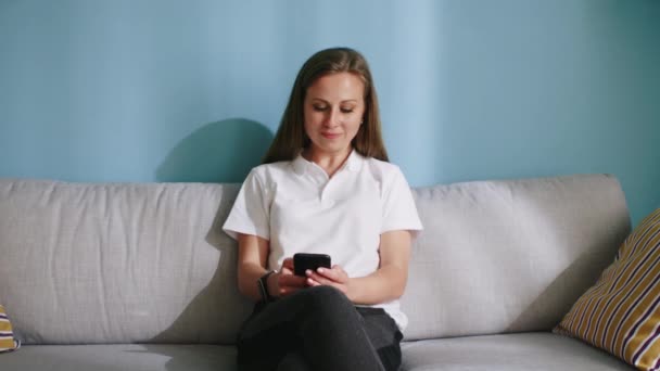 Drukke vrouw gebruikt mobiele telefoon zittend op de bank — Stockvideo