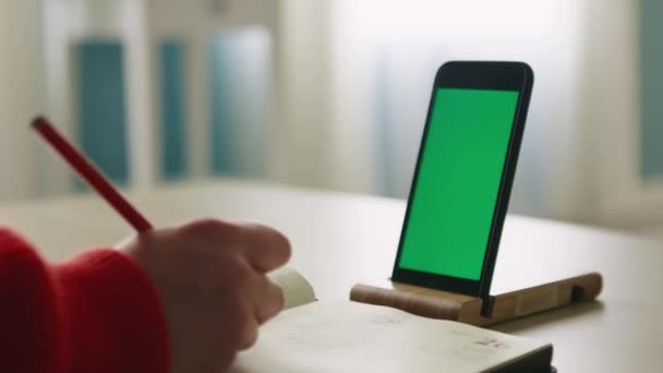 Téléphone portable avec écran vert est placé sur support en bois sur la table — Video