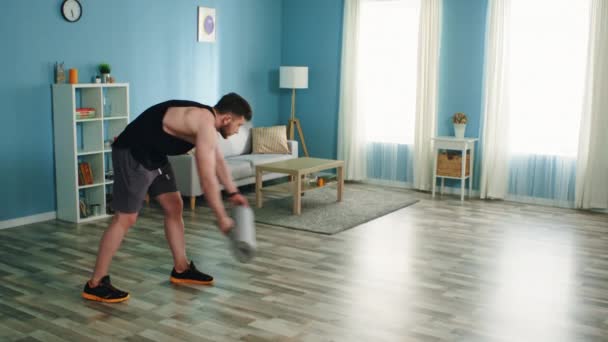 Homem está espalhando Fitness Mat e usa Gadget — Vídeo de Stock