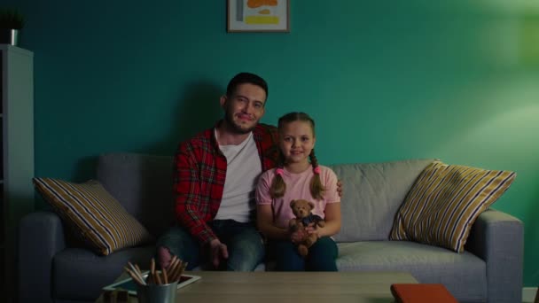 Portré a kislányról és a fiatal férfiról, aki a kanapén ül — Stock videók