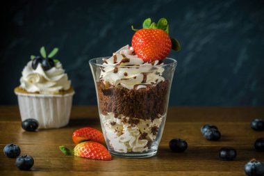 Delisious kek krem ve çilek ile bir taş koyu arka plan.