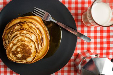 Güzel bir masa örtüsü arka planda kahvaltı için süt ve kahve ile lezzetli krep.