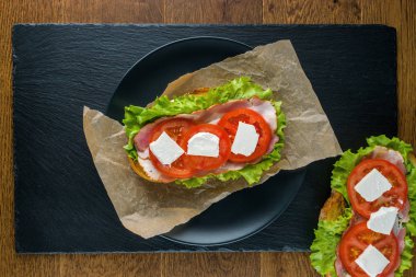 Koyu taş arka plan ile ahşap masada lezzetli sandviçler.