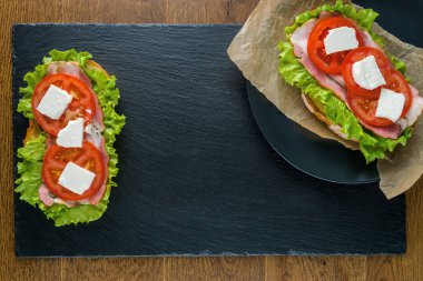 Koyu taş arka plan ile ahşap masada lezzetli sandviçler.