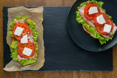 Koyu taş arka plan ile ahşap masada lezzetli sandviçler.