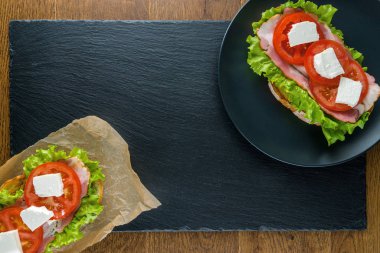 Koyu taş arka plan ile ahşap masada lezzetli sandviçler.