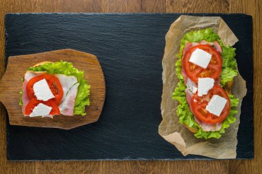 Koyu taş arka plan ile ahşap masada lezzetli sandviçler.