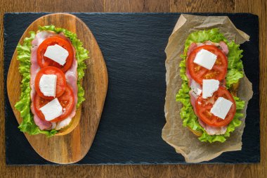 Koyu taş arka plan ile ahşap masada lezzetli sandviçler.