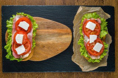 Koyu taş arka plan ile ahşap masada lezzetli sandviçler.