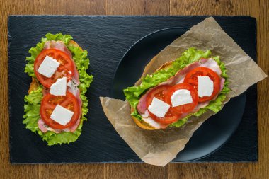 Koyu taş arka plan ile ahşap masada lezzetli sandviçler.