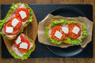 Koyu taş arka plan ile ahşap masada lezzetli sandviçler.