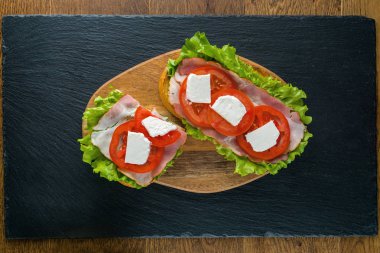 Koyu taş arka plan ile ahşap masada lezzetli sandviçler.