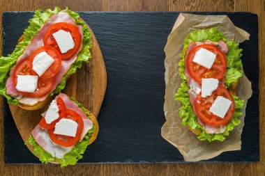 Koyu taş arka plan ile ahşap masada lezzetli sandviçler.