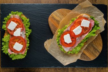 Koyu taş arka plan ile ahşap masada lezzetli sandviçler.