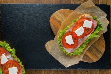 Koyu taş arka plan ile ahşap masada lezzetli sandviçler.