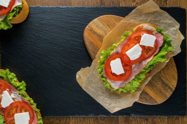 Koyu taş arka plan ile ahşap masada lezzetli sandviçler.