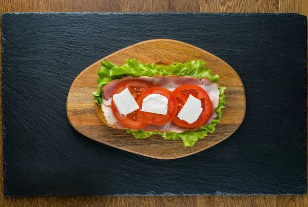 Delicious sandwiches on wooden table with dark stone background. — Stock Photo, Image