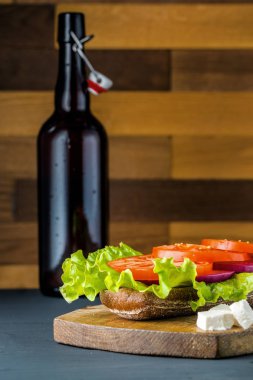 Siyah ahşap arka plan üzerinde salata ile Kahvaltı domates sandviç.